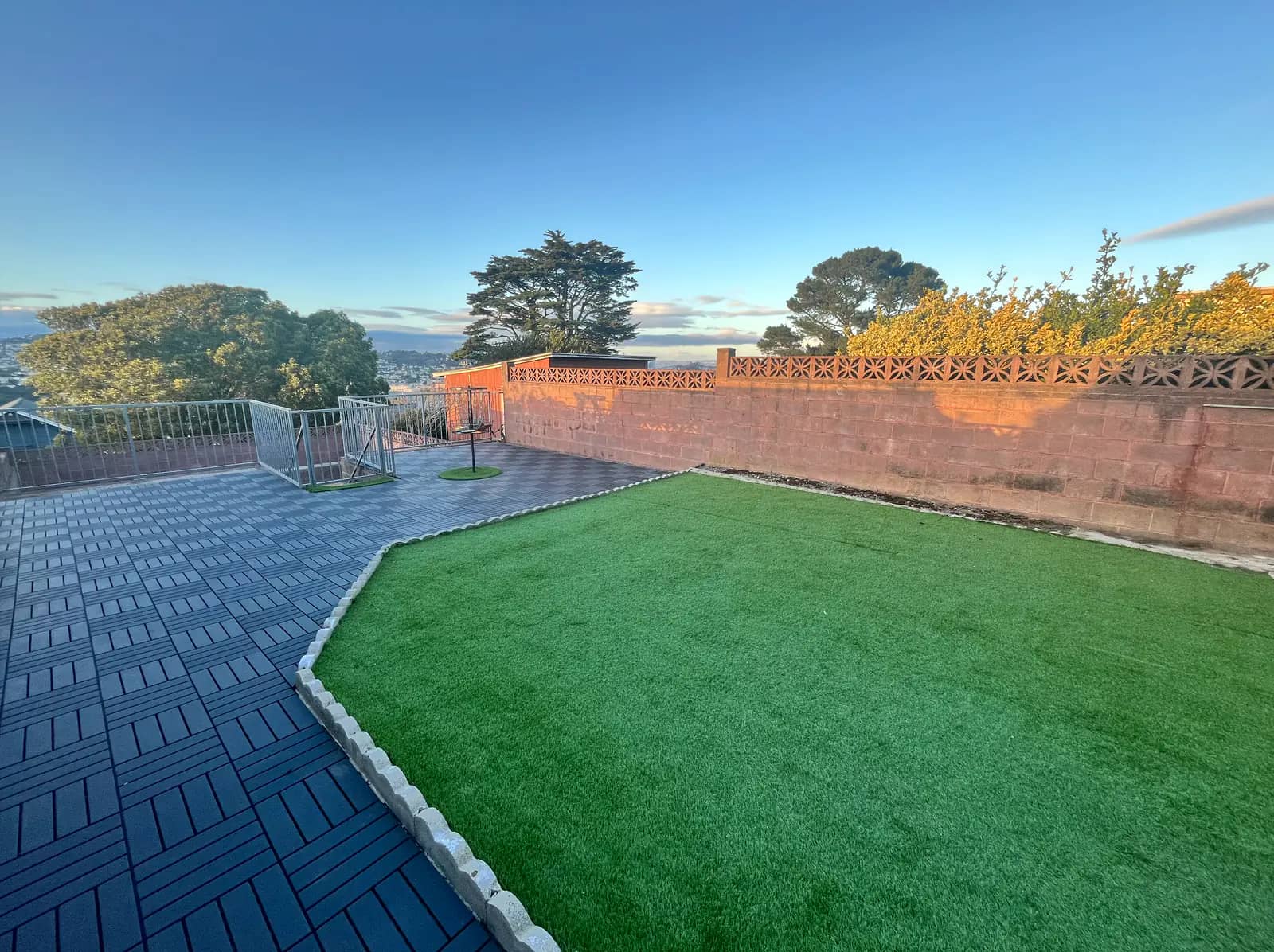 Sunny fenced turf yard and patio with San Francisco views
